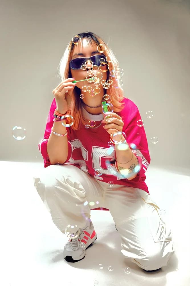 A woman in pink with sunglasses, crouching