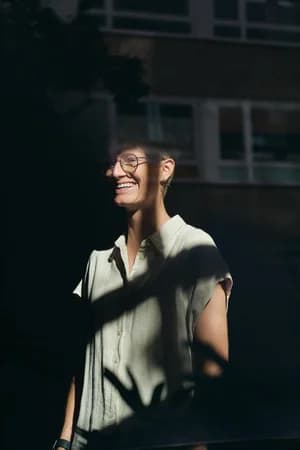 A woman laughing in sunlight and leaf shadows, for Neu & Frei GmbH